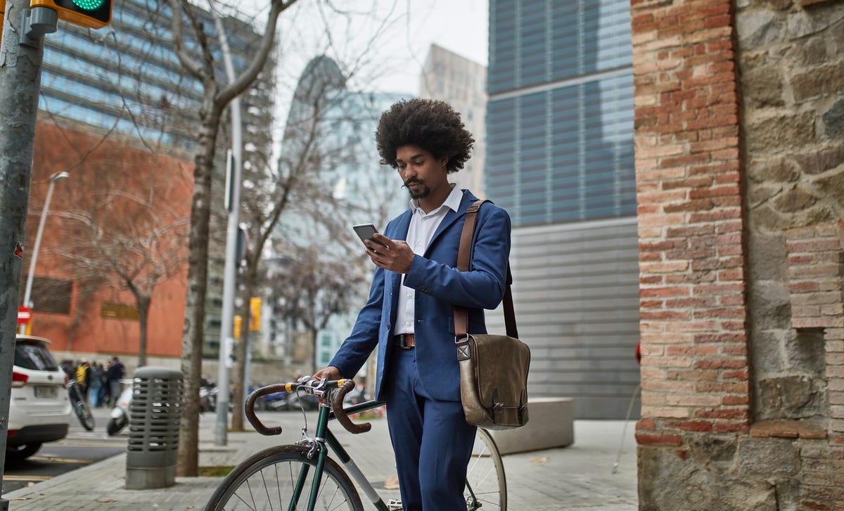Man with a bike looking at Berlitz Algeria's contact on his phone