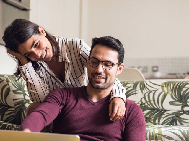 Couple sitting on a couch and looking up intermediate Arabic classes with Berlitz Algeria on a laptop