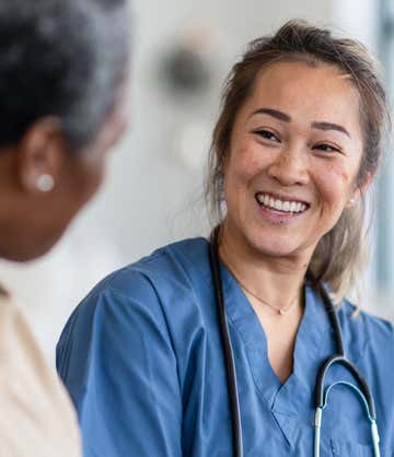 A young nurse smiles at patient.