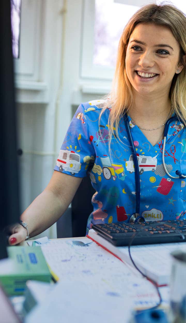 A smiling nurse is working at her computer.