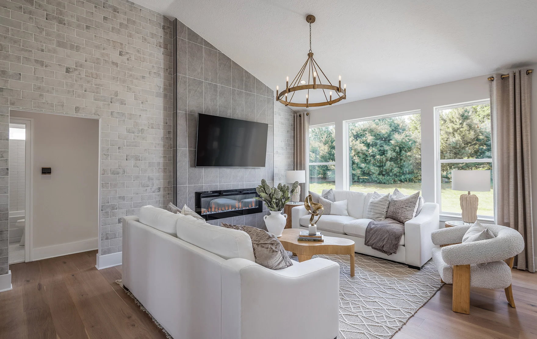 A bright, coastal style living room. Two white sofas face each other over a circular coffee table, a fireplace and television over it.