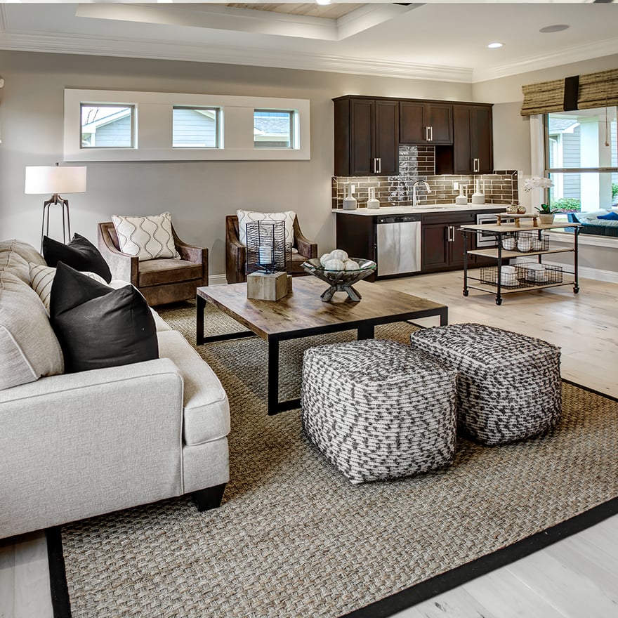 A well-lit living room with a kitchenette area and seating. Neutral tones create a relaxing, comfortable space.