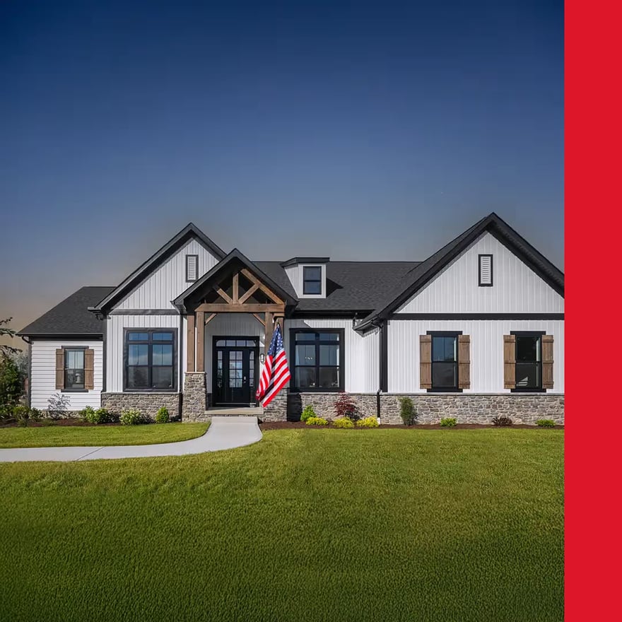A modern farmhouse displays white siding, dark trim, and stone accents. An American flag hangs near the front door, contributing to the home's patriotic ambiance.