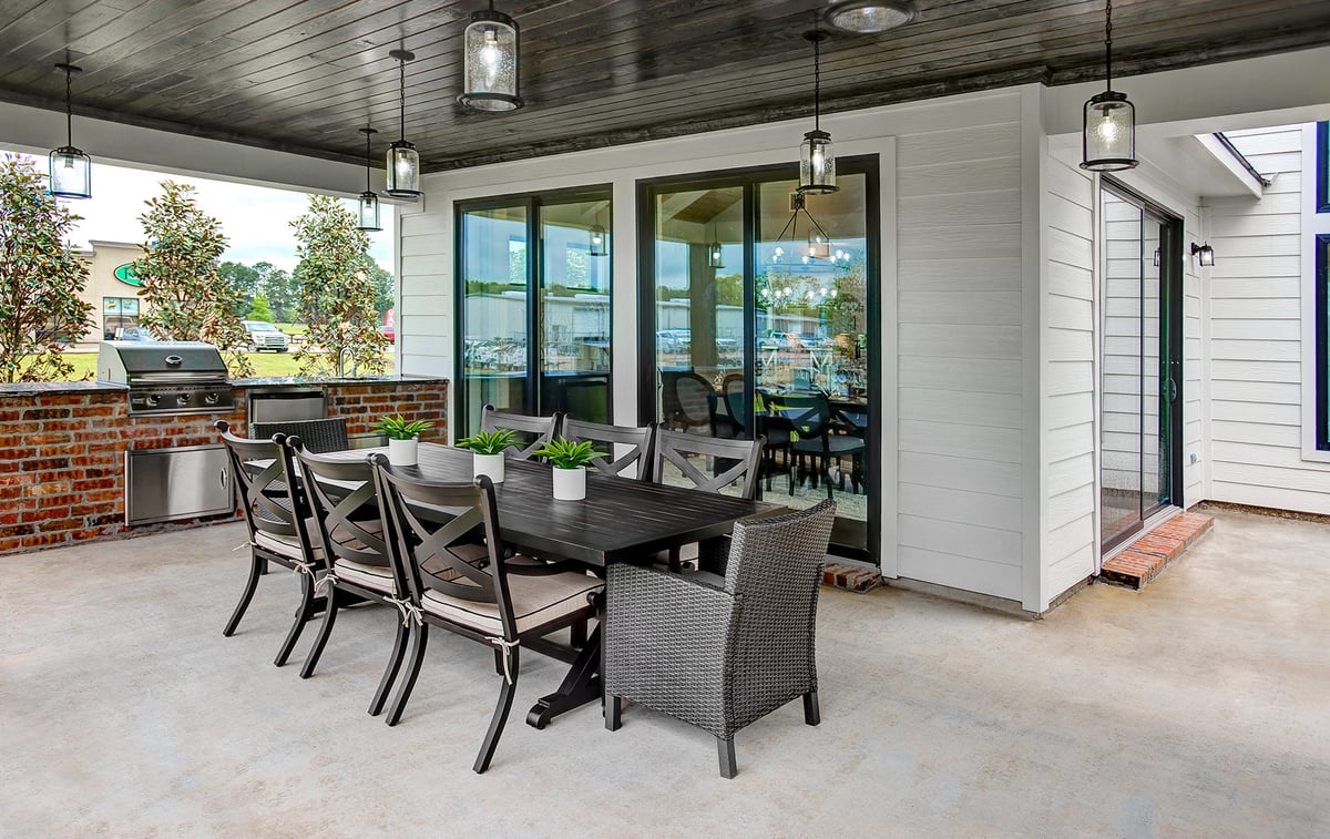 Outdoor dining area with a black wooden table and matching chairs under pendant lights. 