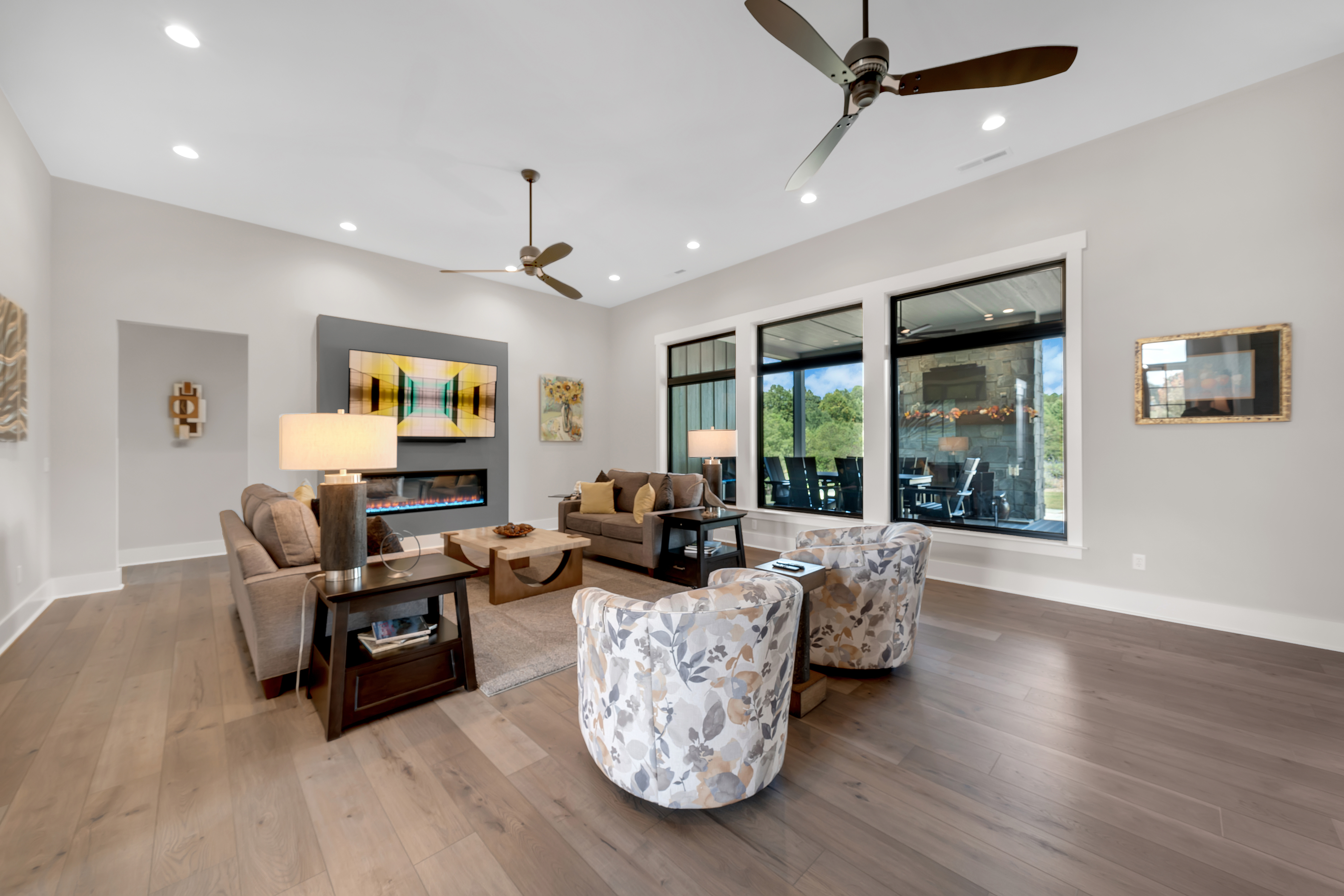 Great room with 4 love seats. There are light wood floors and 3 large windows.