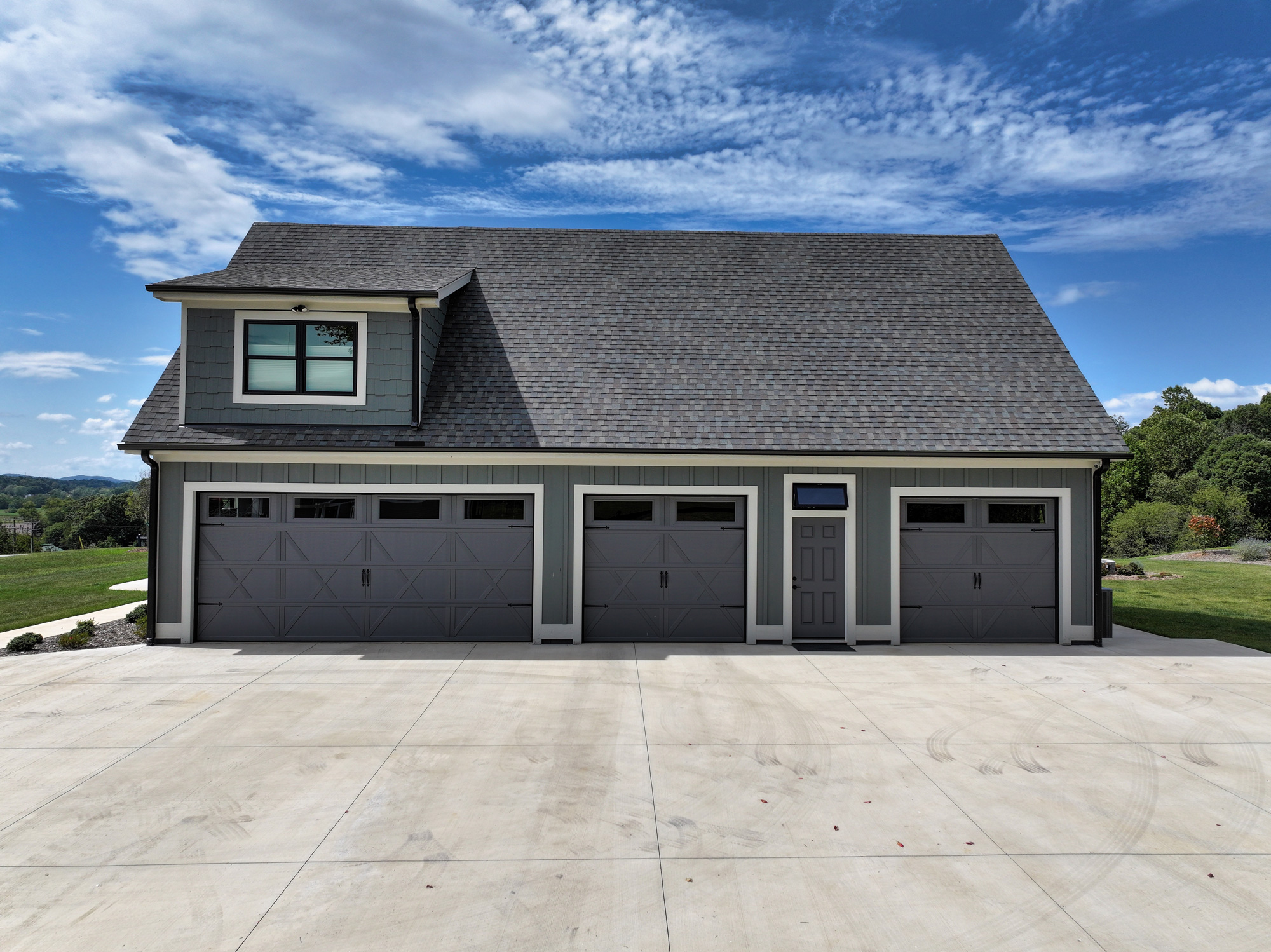 grey 4 car garage with grey roof with blue skies
