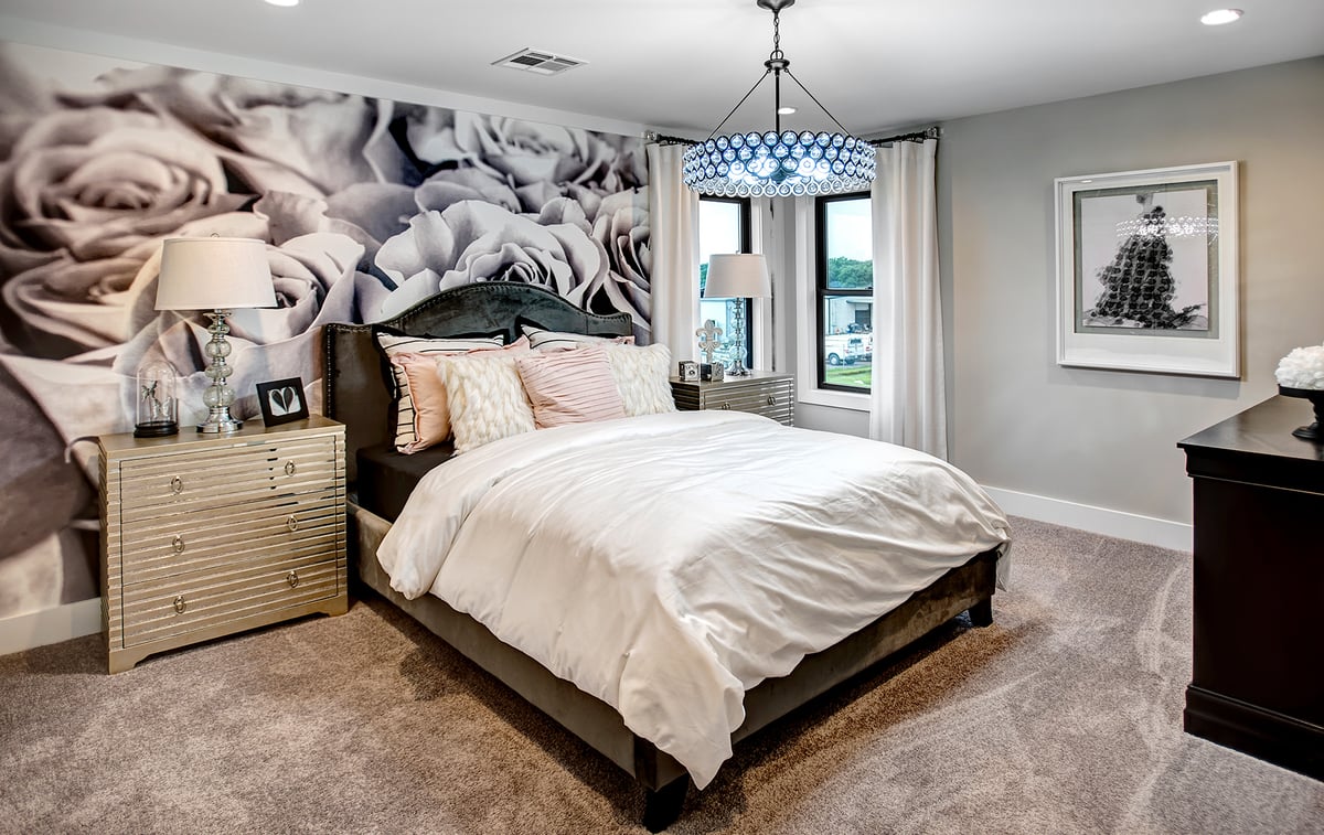 This is a model bedroom. The design is centered around a monochrome floral wall and matching chandelier.