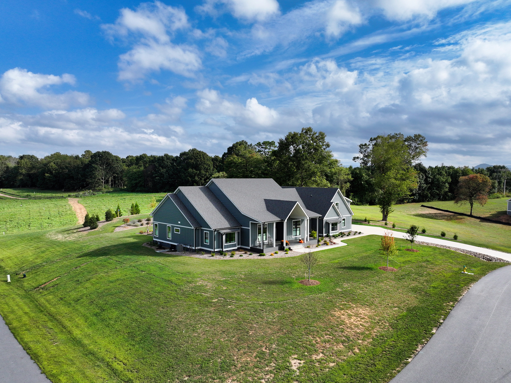 Aerial view of a large farmhouse with dark blue siding and grey roof.