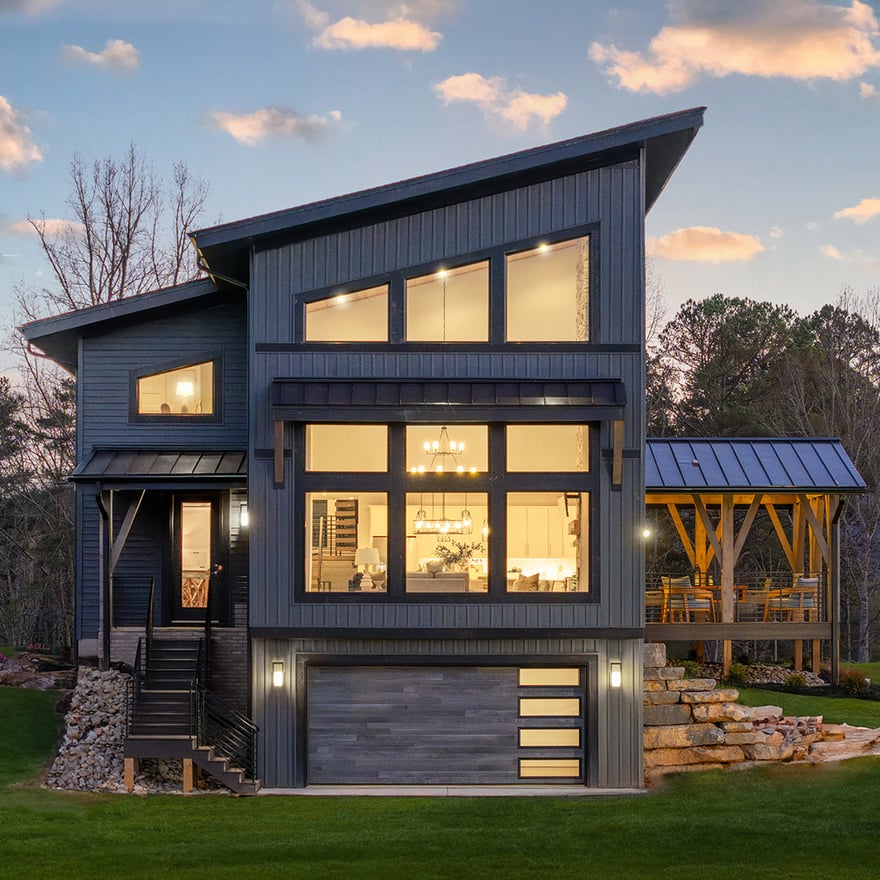 Contemporary two-story home with ample natural light. The home features modern architecture, a garage, and a covered outdoor space.