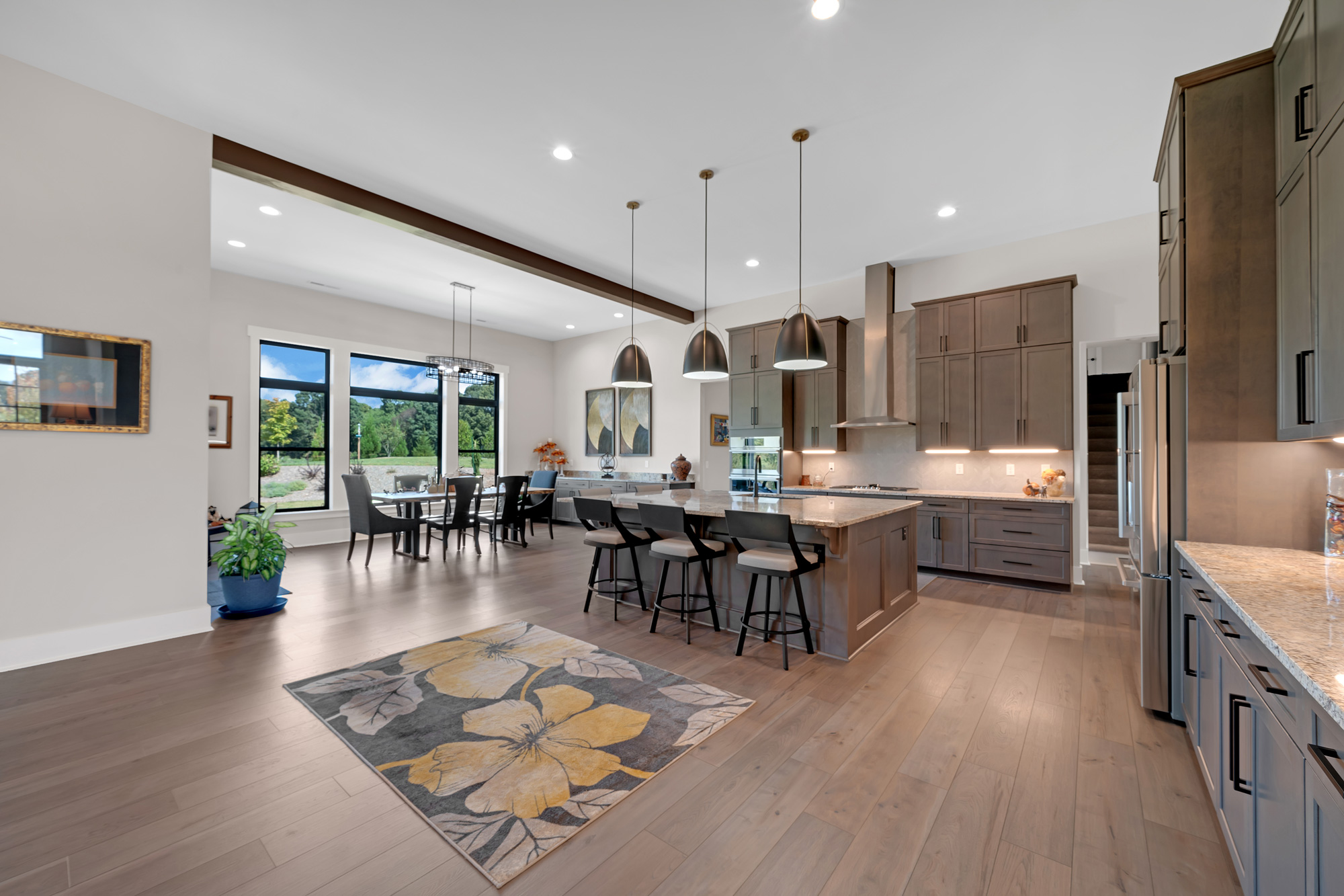 Kitchen with brown cabinets. There is a large island in the center of the room with 3 bar stools along the side.