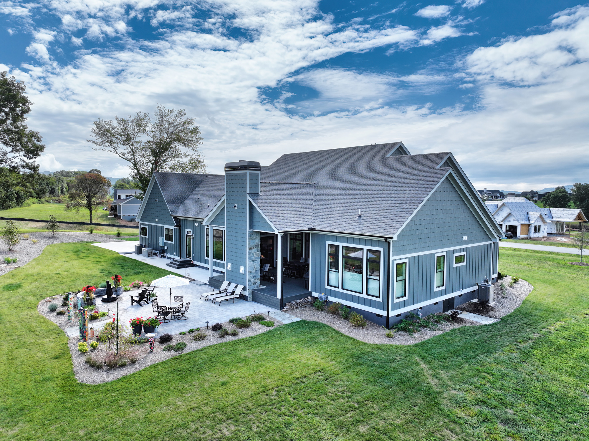 side view of a large blue house on green grass on a sunny day.