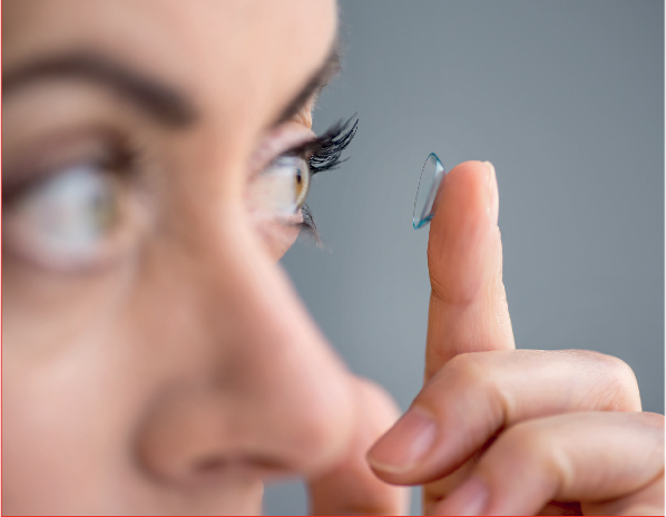 Woman inserting contact lens in the mirror