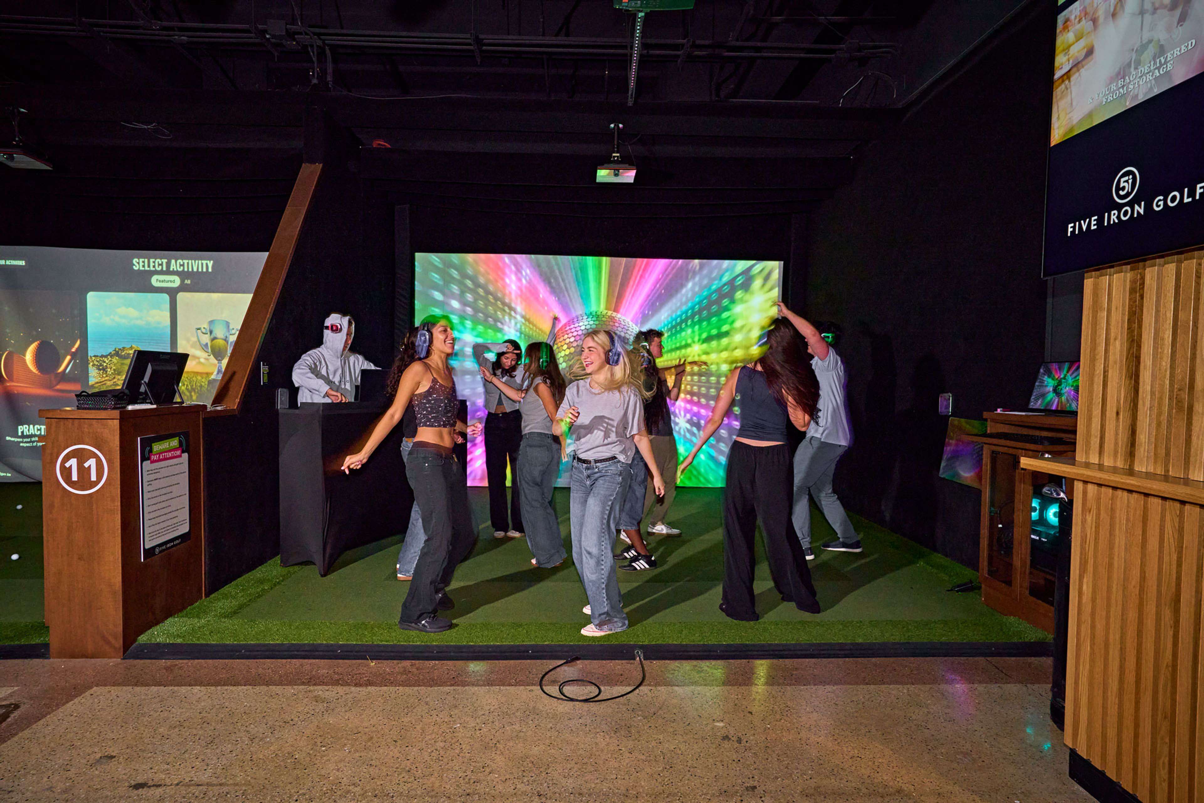 Group dancing on a Five Iron Golf simulator bay during a holiday party