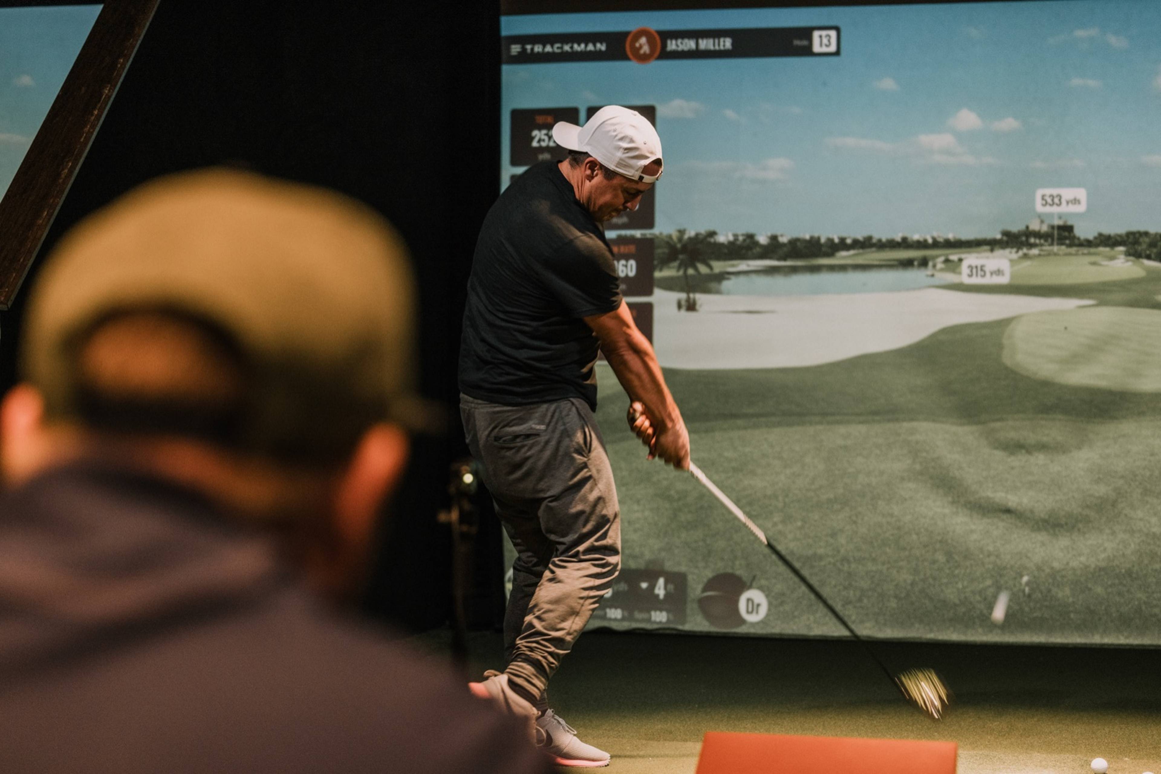 Guest swinging in a golf simulator bay