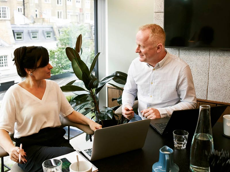 Dos profesionales conversando en inglés sobre actividades de la rutina diaria en un entorno laboral, parte de las clases temáticas de Berlitz