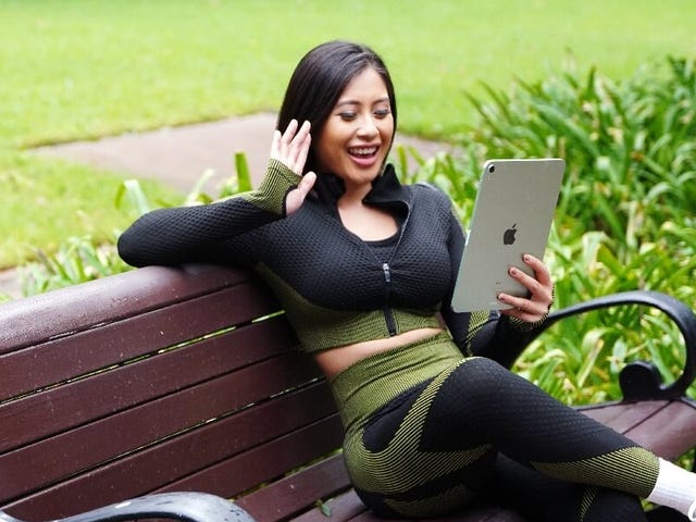 Estudiante sonriente en una clase virtual de idiomas con Berlitz desde un parque, combinando su estilo de vida activo con el aprendizaje flexible.