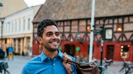 Hombre sonriente caminando por una ciudad europea mientras aprende italiano con Berlitz.