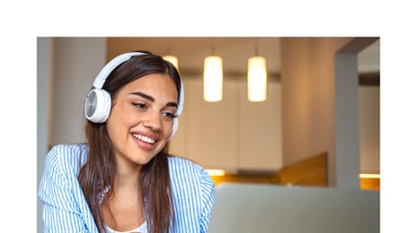 Mujer estudiando inglés online con audífonos desde casa, en clase virtual de Berlitz.