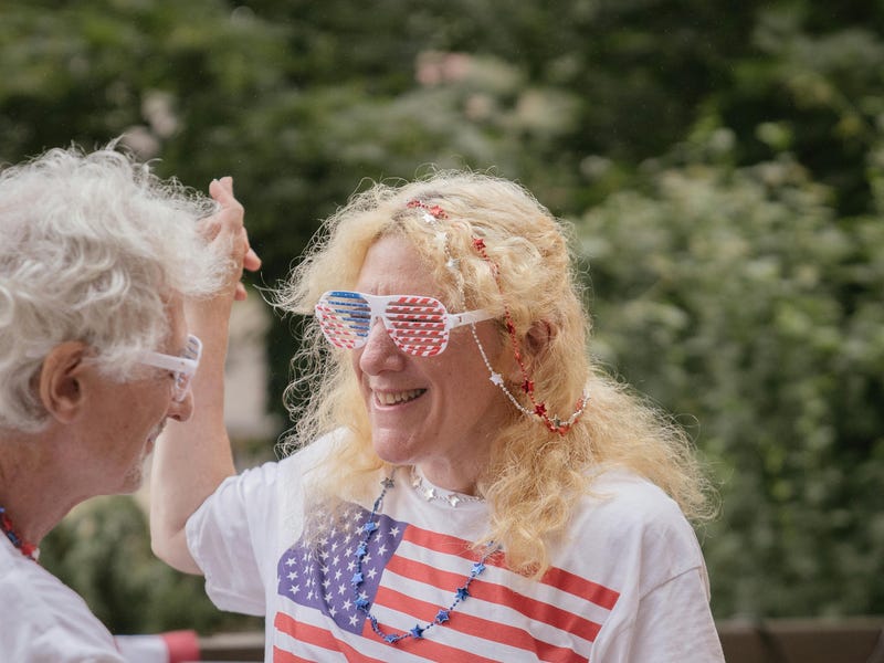 Abuelos bailando con la bandera del día de la Independencia de Estados Unidos.