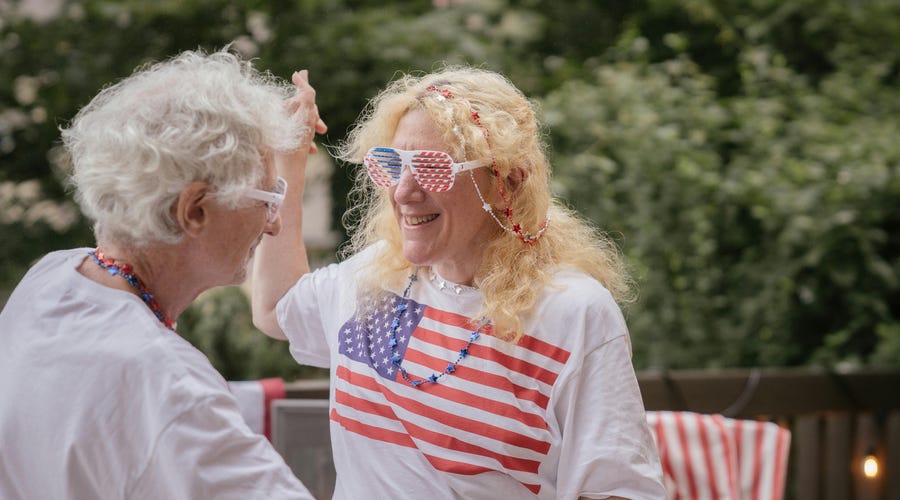 Abuelos bailando con la bandera del día de la Independencia de Estados Unidos.