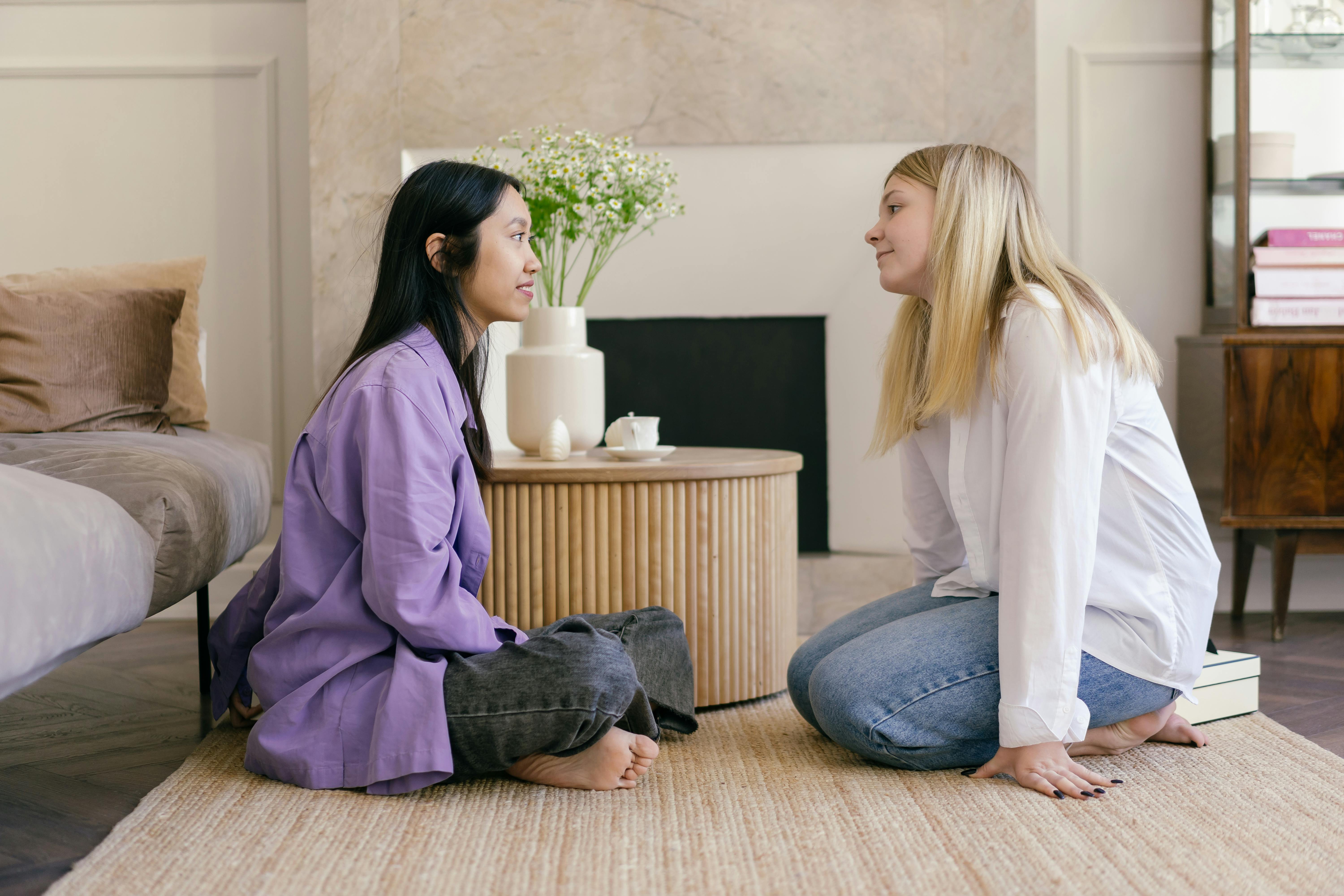 Dos amigas sentadas en el piso haciendo comentarios en inglés.
