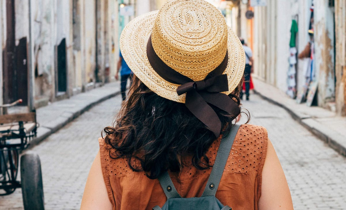 Mujer caminando por una calle colonial con mochila y sombrero típico, imagen representativa de estudiantes internacionales que viajan y aprenden idiomas en Colombia con Berlitz