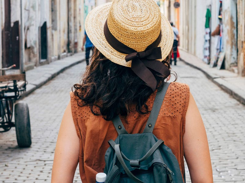 Mujer caminando por una calle colonial con mochila y sombrero típico, imagen representativa de estudiantes internacionales que viajan y aprenden idiomas en Colombia con Berlitz