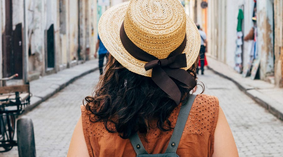 Mujer caminando por una calle colonial con mochila y sombrero típico, imagen representativa de estudiantes internacionales que viajan y aprenden idiomas en Colombia con Berlitz