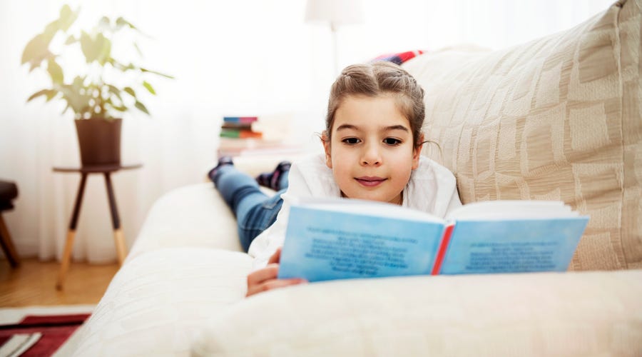 Niña leyendo viendo actividades para niños en casa durante las vacaciones de navidad