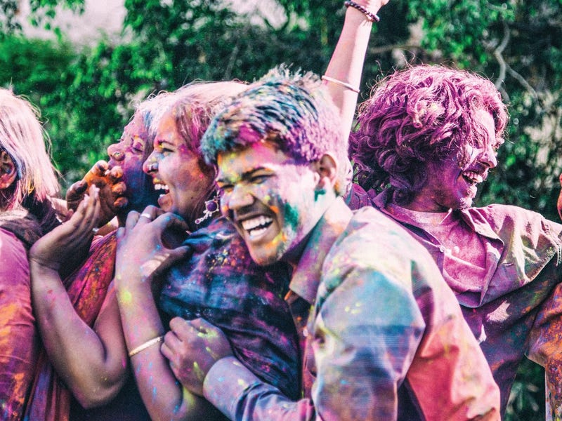 un grupo de jóvenes bañados en pintura y sonriendo en inglés.