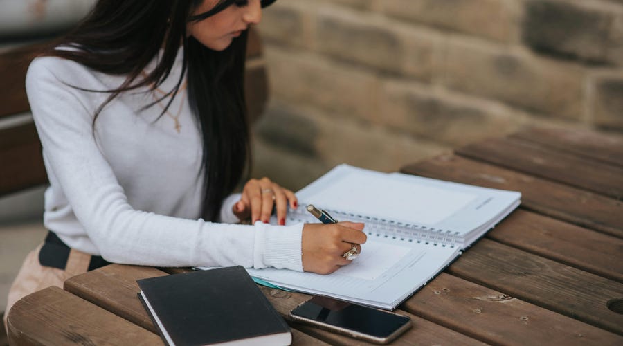 Mujer estudiando temas de inglés a1 con un cuaderno.