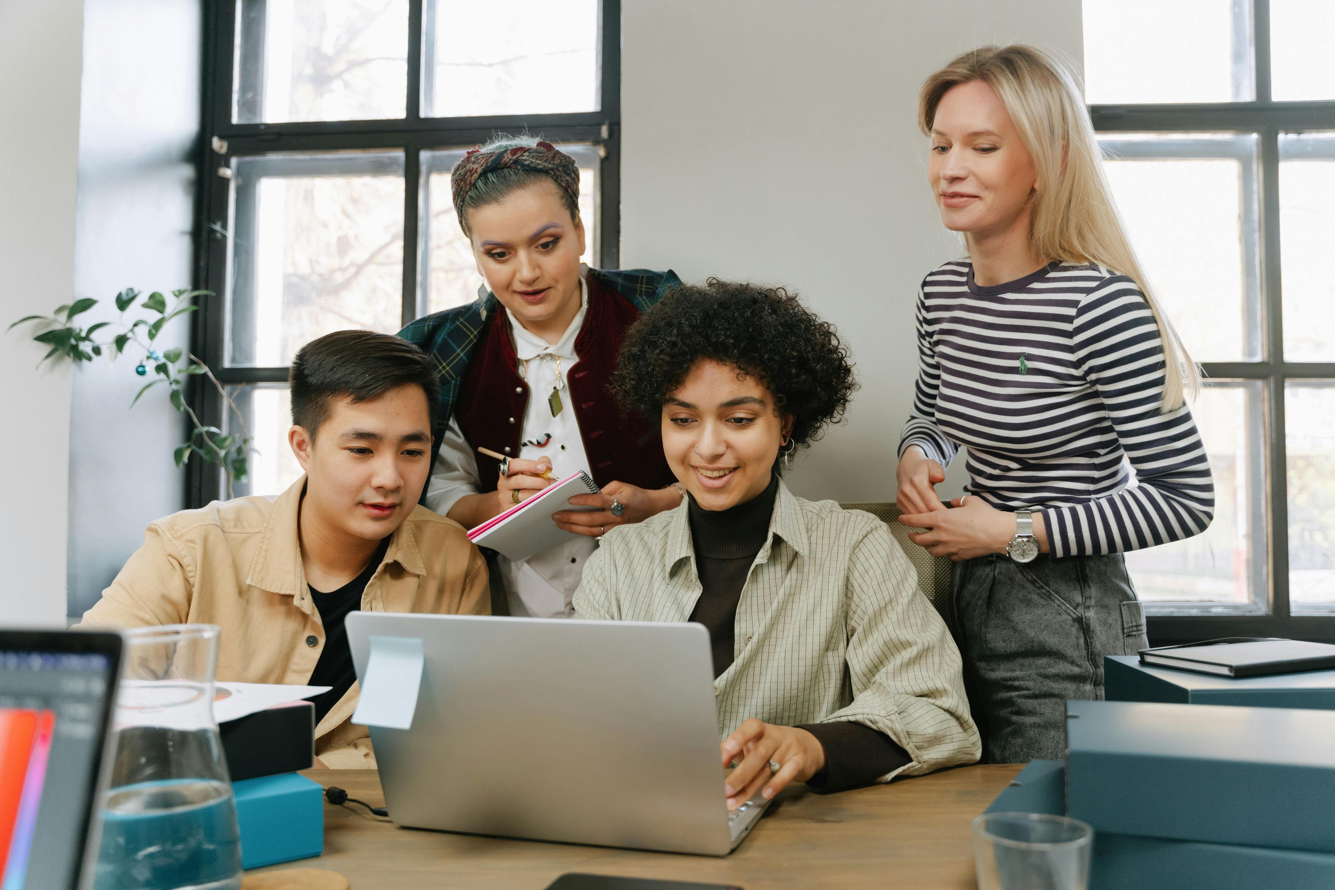 Grupo de adultos reunidos frente a una computadora portátil, estudiando sobre el proceso de aprendizaje.