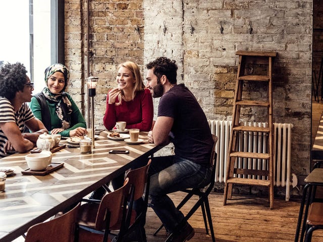 Grupo de jóvenes de diversas culturas compartiendo en una cafetería, símbolo de inclusión, conexión global y el poder del aprendizaje de idiomas con Berlitz.
