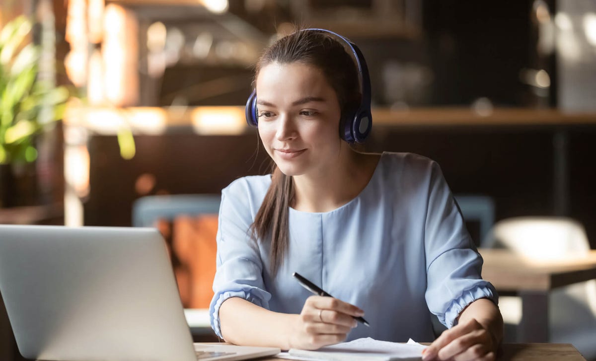 Mujer presentando el examen TOEFL en línea con audífonos, luego de prepararse en un curso de certificación de inglés con Berlitz