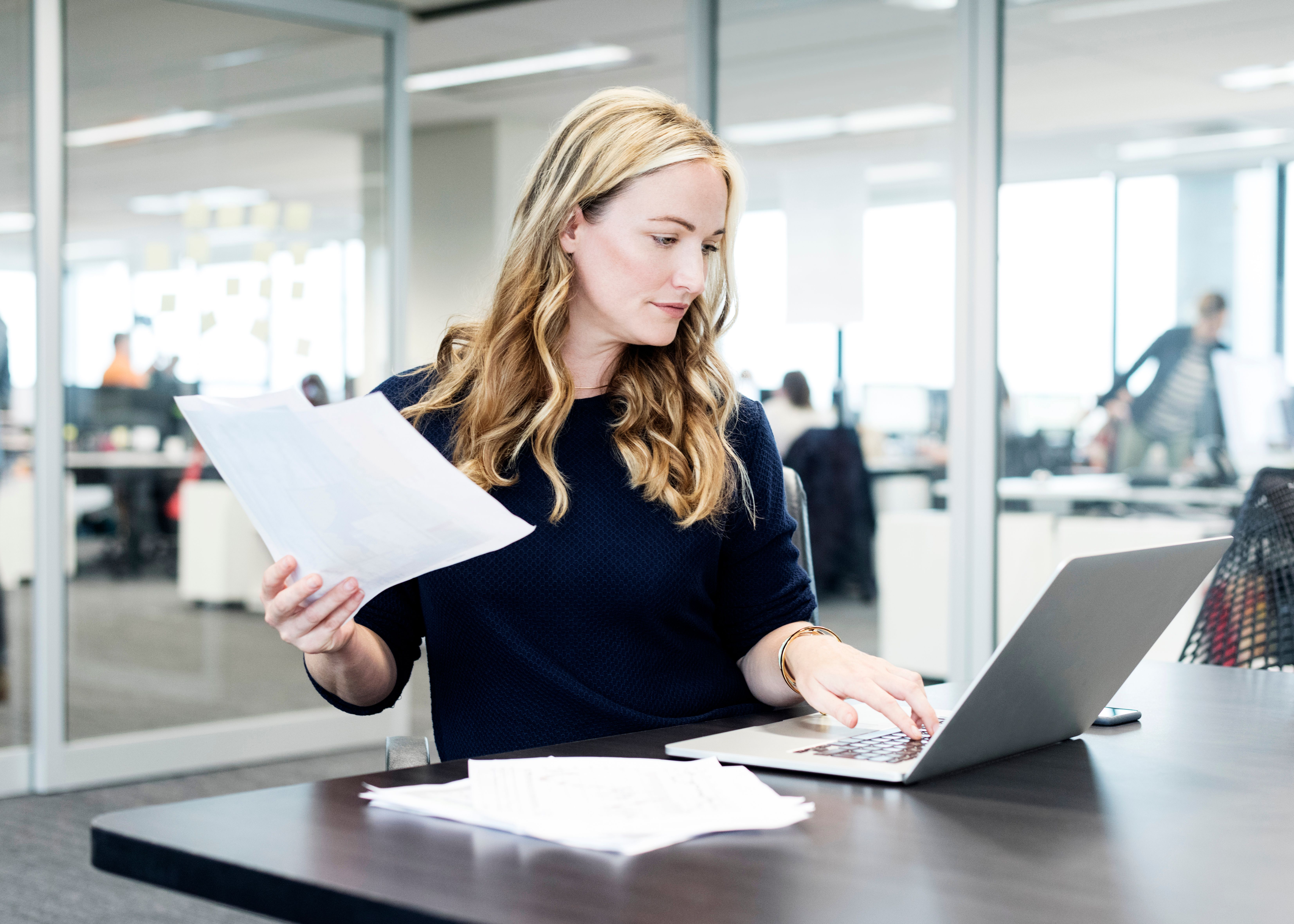 Mujer en la oficina trabajando mientras practica el inglés.