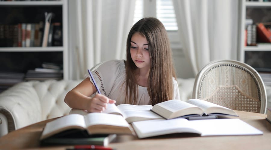 Chica estudiando con libros las opciones de expresiones de cortesía en inglés.