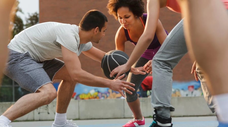 un grupo de adultos jóvenes jugando baloncesto