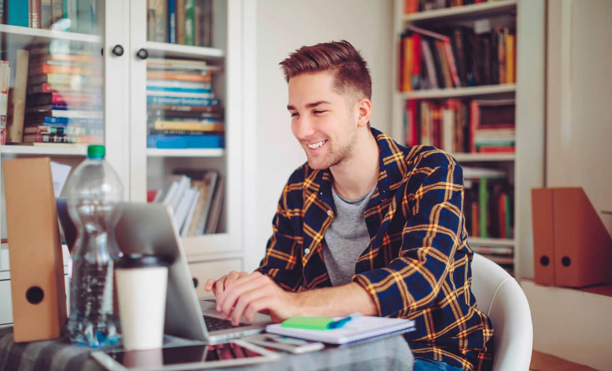 Joven practicando inglés desde casa con su computador portátil, ideal para ilustrar clases online o programas de autoestudio de Berlitz