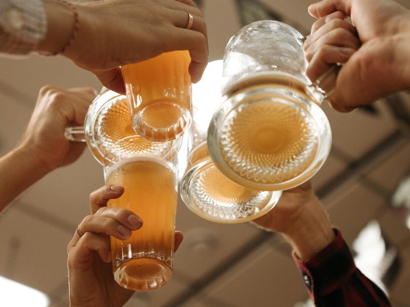 Personas celebrando en un bar con bebidas en portugués.