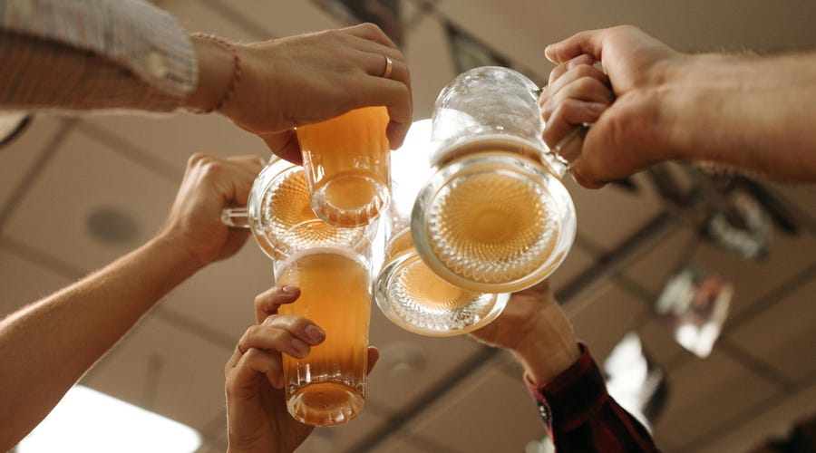 Personas celebrando en un bar con bebidas en portugués.