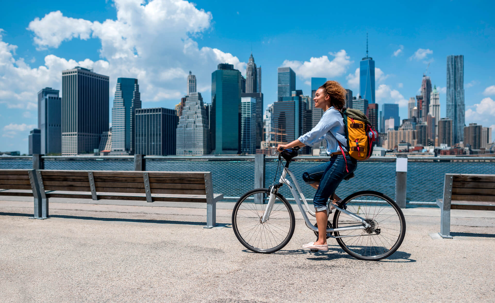 Mujer andando en bicicleta por Nueva York mientras estudia inglés con Berlitz, rodeada del skyline de Manhattan