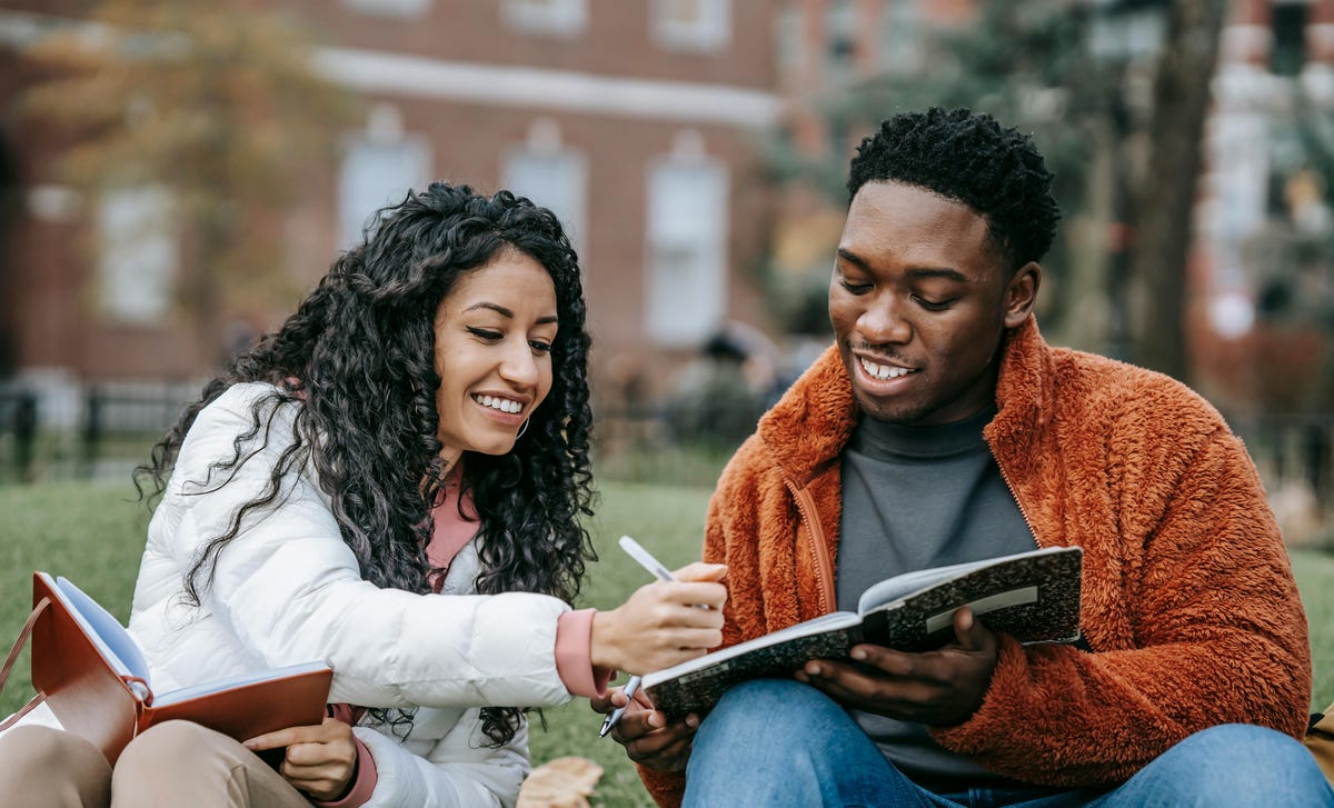 Dos amigos estudiando en el jardín lo que aprendieron en el mejor centro de idiomas de Colombia.