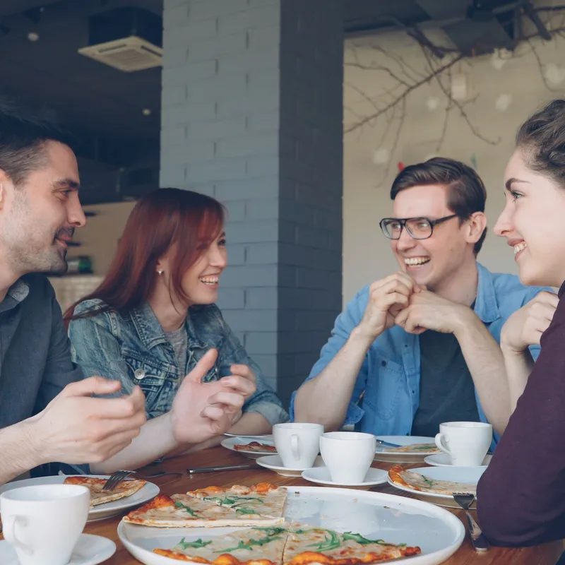 Un grupo de amigos hablando sobre personalidad mientras comen pizza.