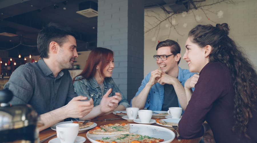 Un grupo de amigos hablando sobre personalidad mientras comen pizza.