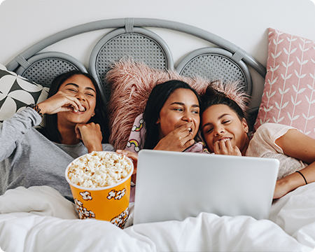 Girls being cozy watching a movie in bed