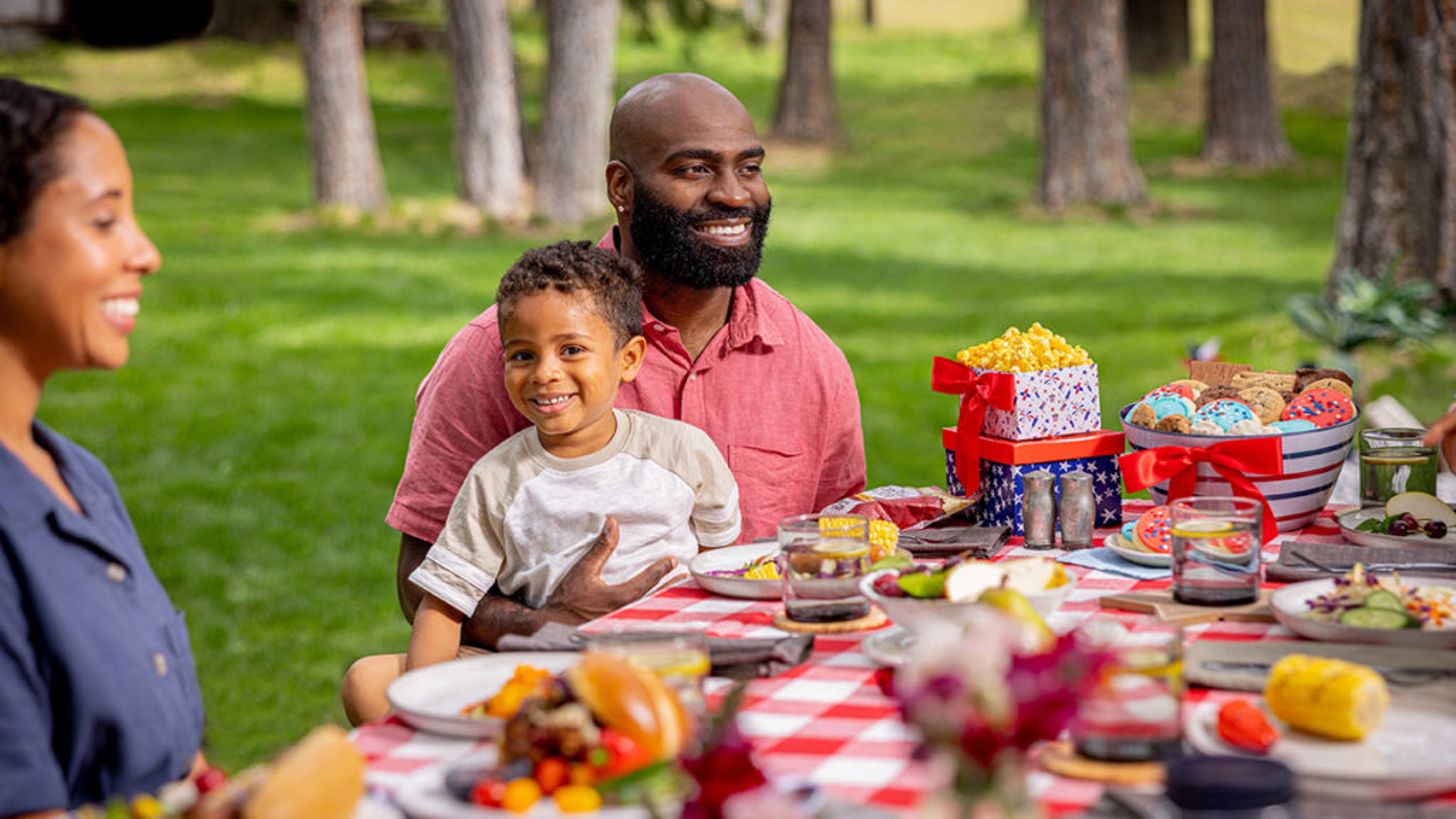 Father and son sitting at a picnic table laid with food.