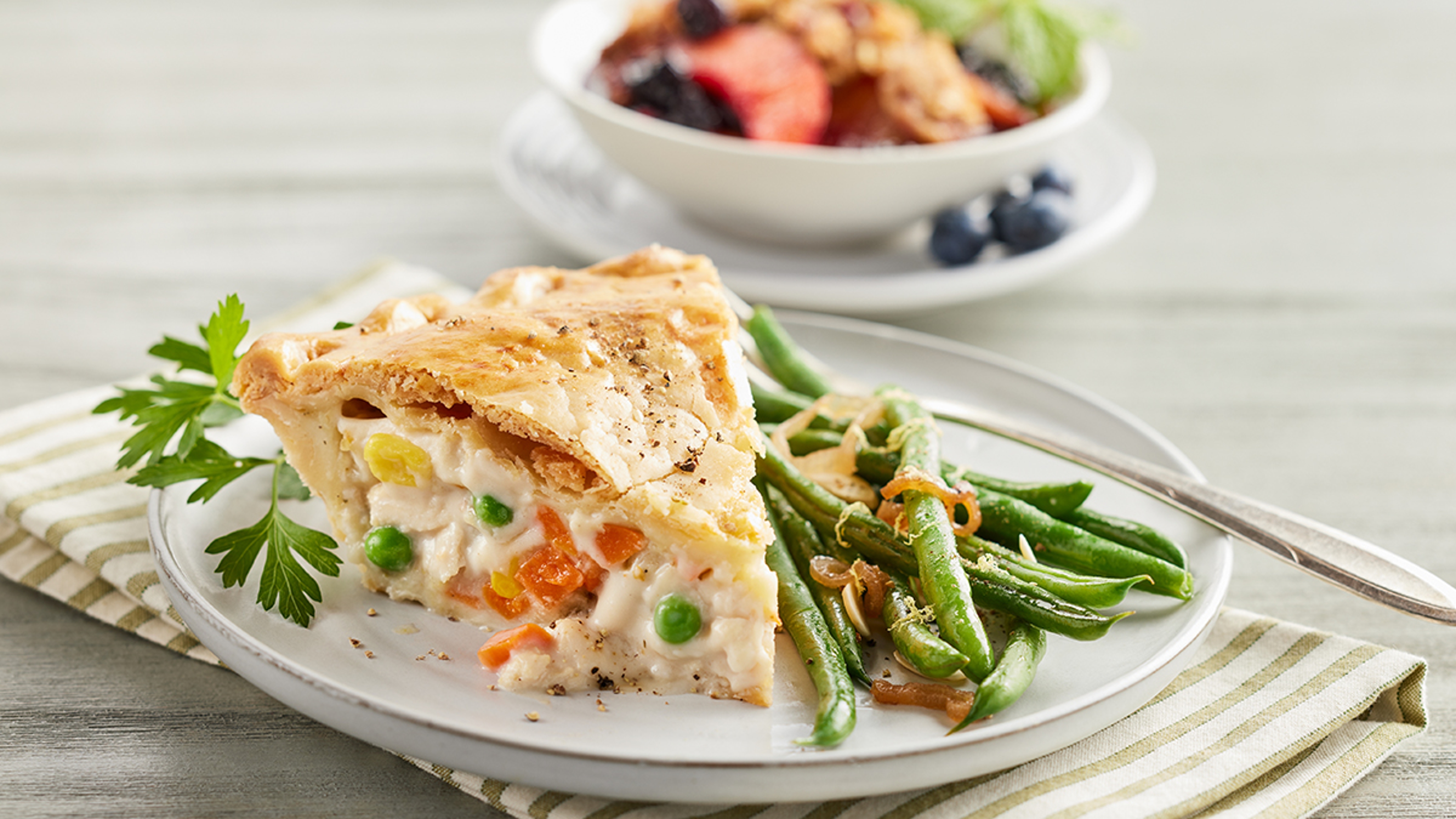 Holiday prepared meals with a slice of pot pie on a plate with green beans.