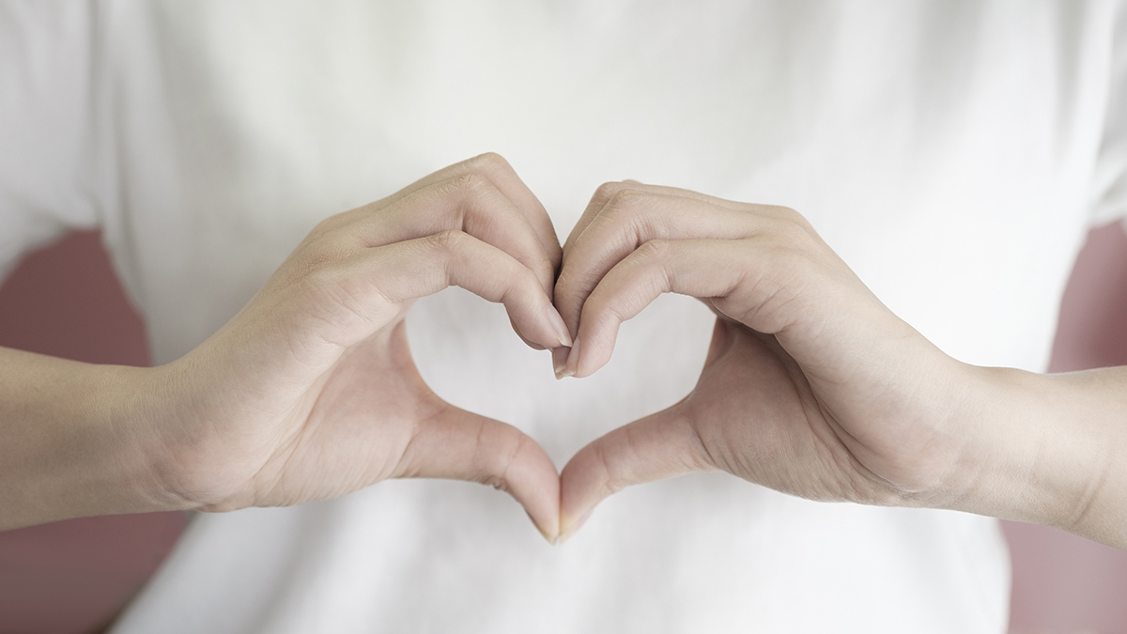 Article Cards Featured Image woman making hands in heart shape, heart health insurance, socia