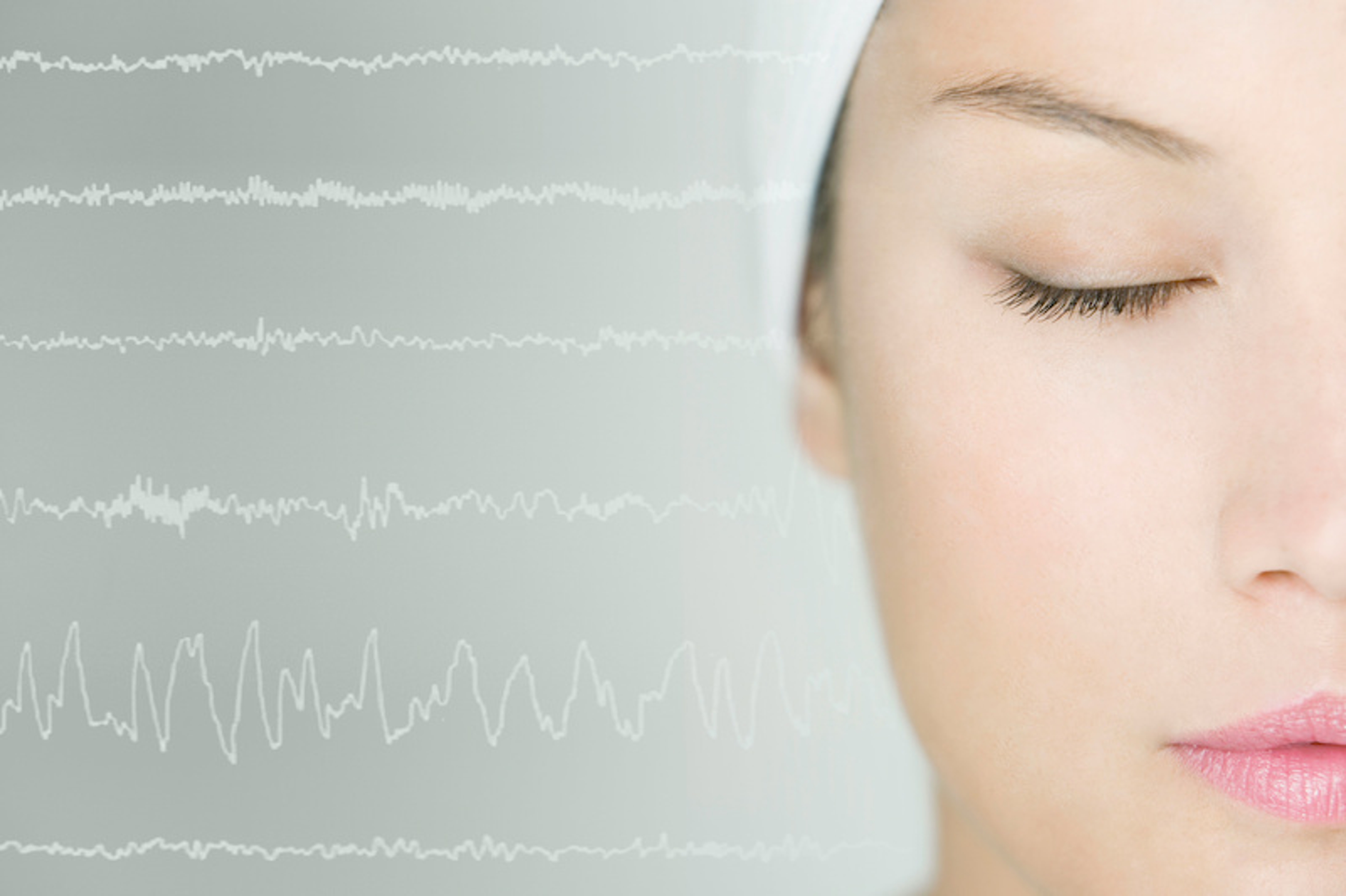 Sleeping woman with brain scan waves in background.