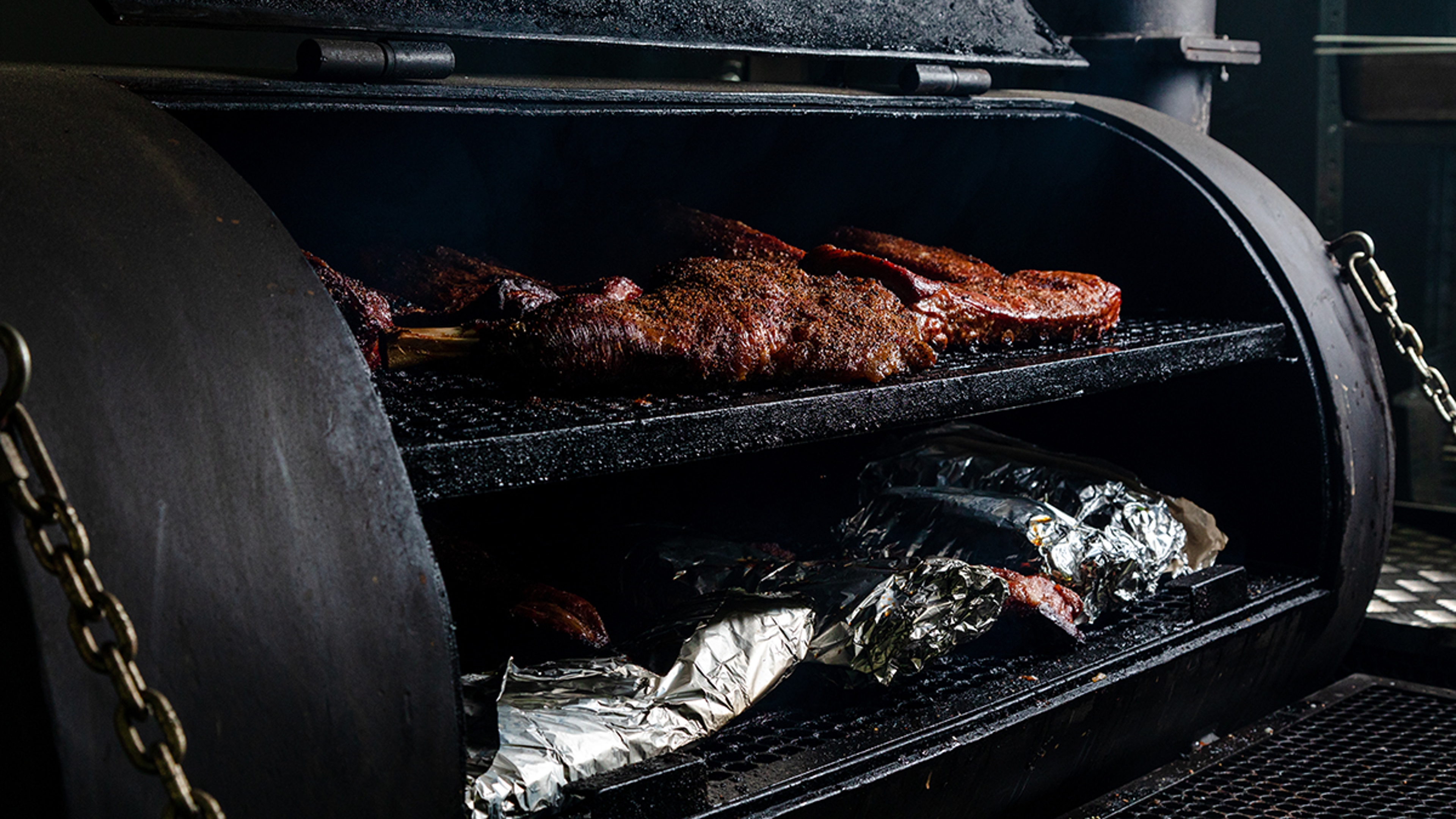 difference between grilling, barbecue, and smoking smoker with seasoned meat in it.